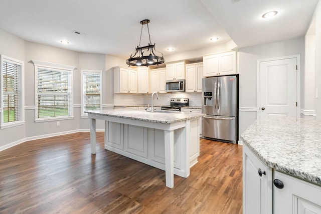 kitchen featuring light stone countertops, dark wood-type flooring, pendant lighting, and appliances with stainless steel finishes