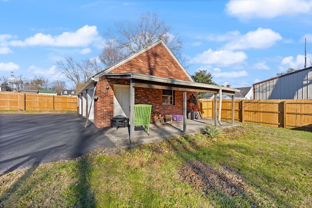 back of house featuring a lawn, a patio area, and a garage