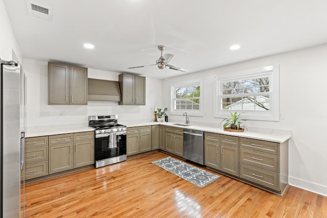 kitchen with custom exhaust hood, sink, ceiling fan, light wood-type flooring, and stainless steel appliances