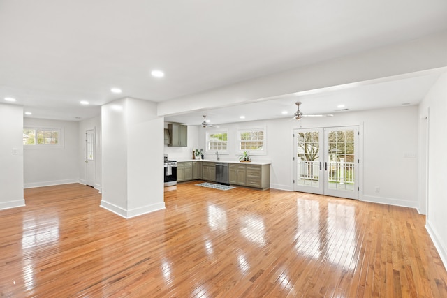 unfurnished living room featuring a healthy amount of sunlight, light wood-type flooring, sink, and french doors