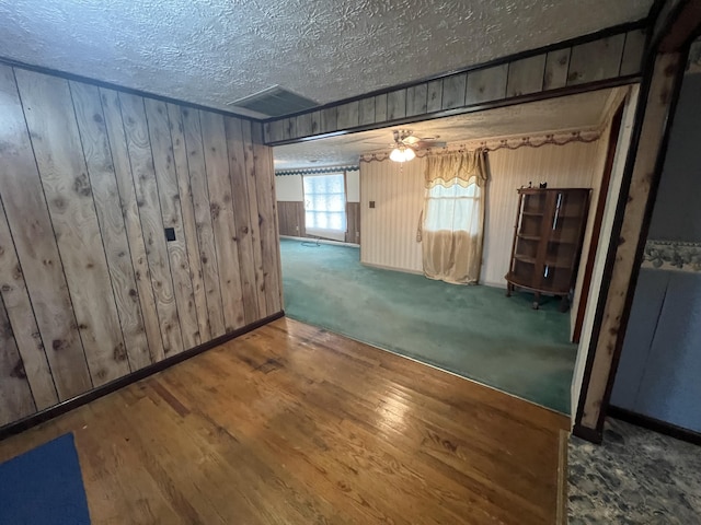 basement featuring hardwood / wood-style floors, a textured ceiling, and wooden walls