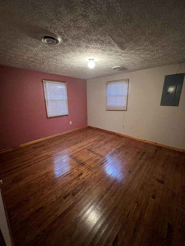 unfurnished room with electric panel, hardwood / wood-style floors, and a textured ceiling