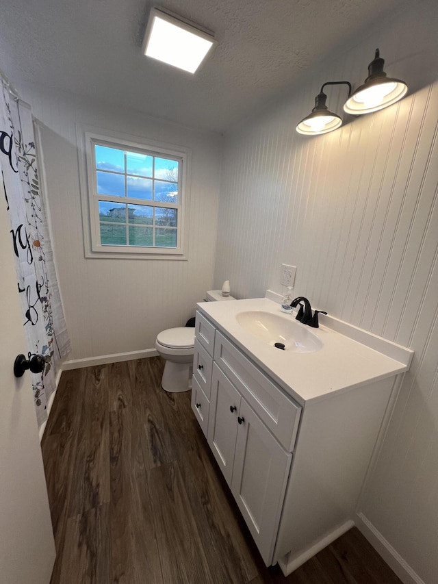 bathroom with hardwood / wood-style floors, vanity, toilet, and a textured ceiling