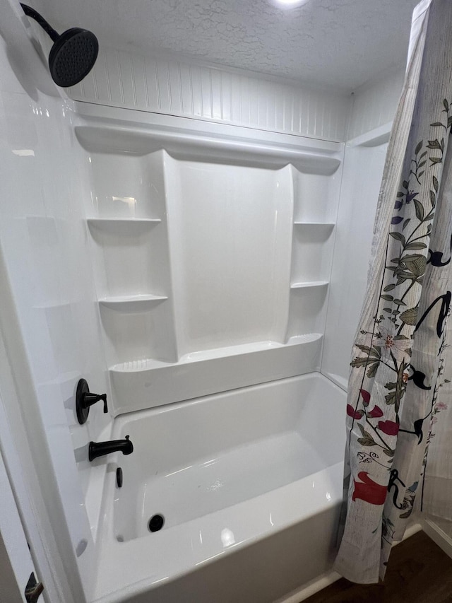 bathroom with shower / tub combo with curtain, wood-type flooring, and a textured ceiling