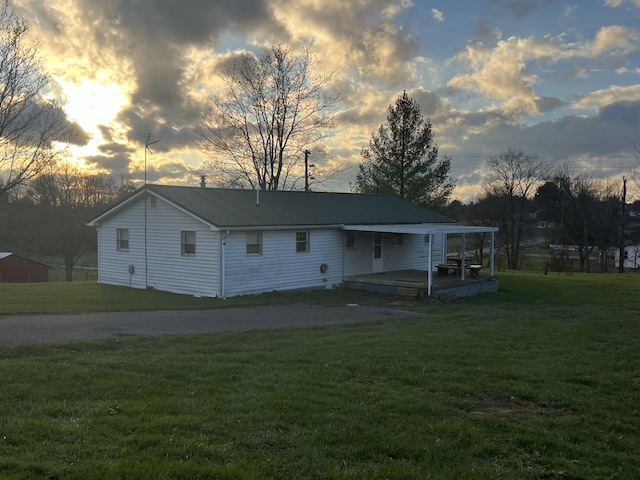 back house at dusk featuring a lawn