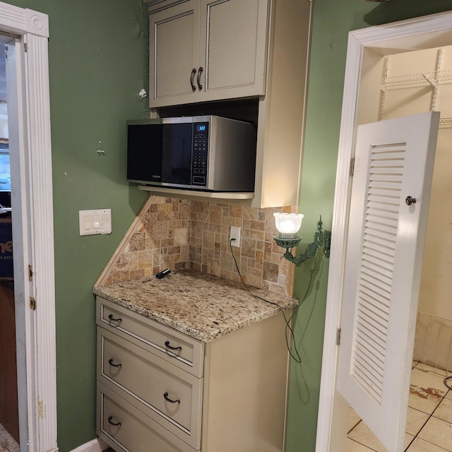 kitchen with light stone countertops, light tile patterned floors, tasteful backsplash, and gray cabinets