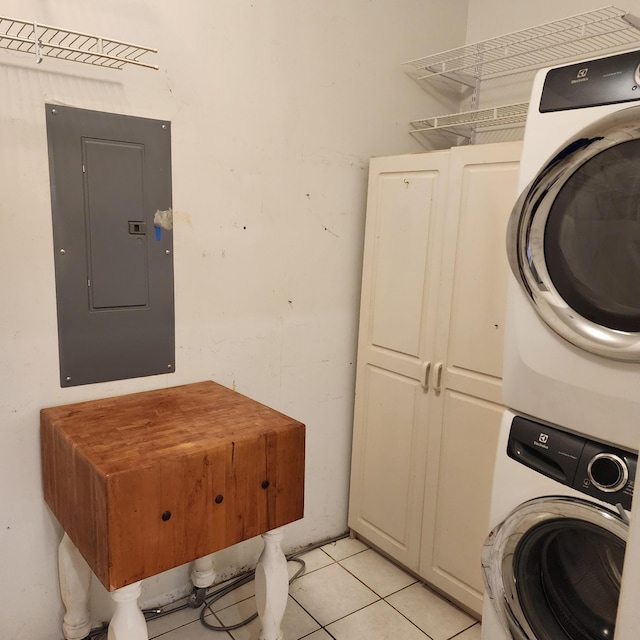 clothes washing area with cabinets, light tile patterned floors, electric panel, and stacked washer and dryer