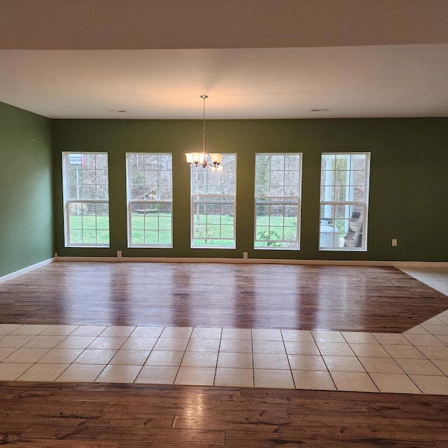 spare room with light hardwood / wood-style flooring and an inviting chandelier