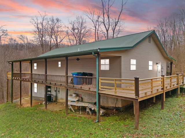 back house at dusk with central AC unit and a deck