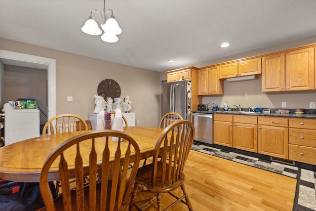 kitchen with sink, stainless steel appliances, light hardwood / wood-style flooring, a chandelier, and decorative light fixtures