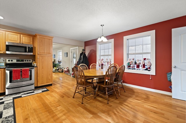 dining space featuring a chandelier, a textured ceiling, and light hardwood / wood-style floors