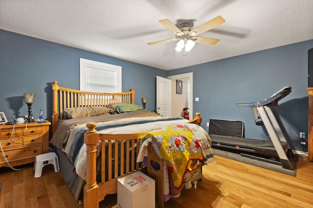 bedroom with wood-type flooring, a textured ceiling, and ceiling fan