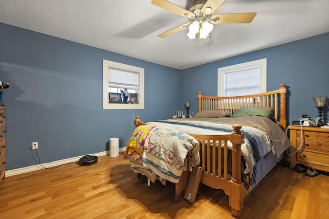 bedroom featuring hardwood / wood-style flooring, ceiling fan, a textured ceiling, and multiple windows