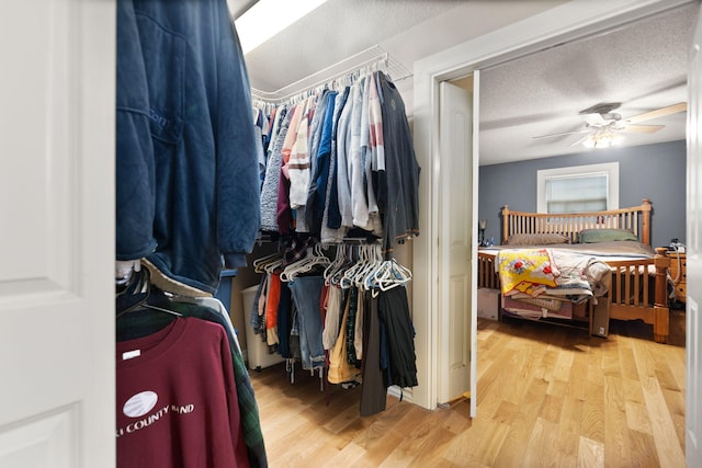 walk in closet with light wood-type flooring and ceiling fan