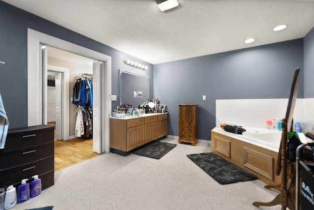 bathroom featuring hardwood / wood-style floors, vanity, a textured ceiling, and a tub