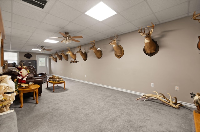 interior space featuring carpet flooring, a drop ceiling, and ceiling fan