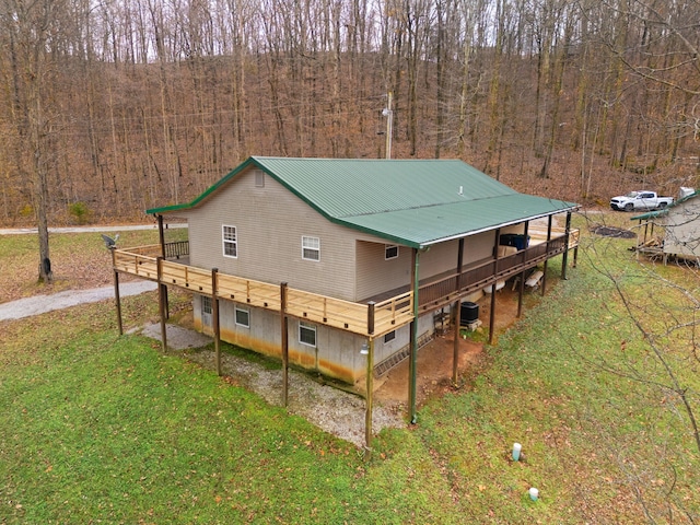 rear view of property featuring central AC unit, a deck, and a yard