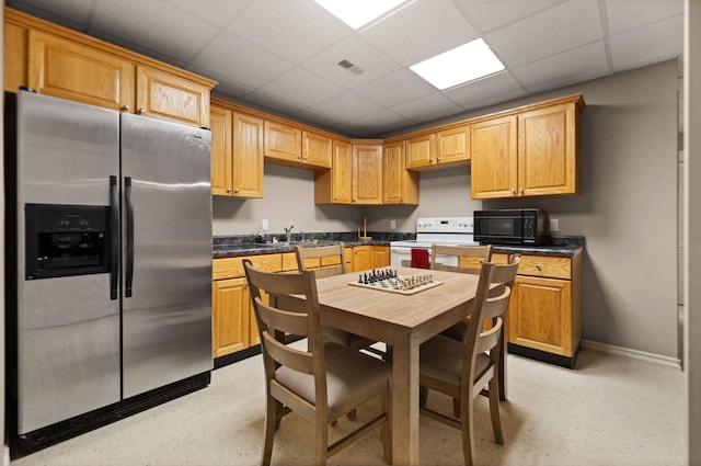 kitchen featuring electric range, a drop ceiling, stainless steel refrigerator with ice dispenser, and sink