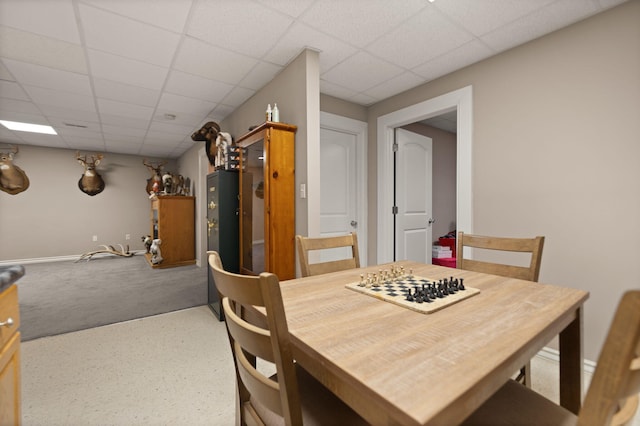 carpeted dining area featuring a paneled ceiling