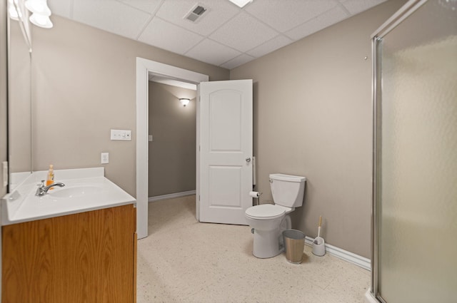 bathroom featuring a paneled ceiling, vanity, toilet, and a shower with door