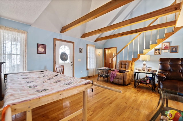 dining area featuring hardwood / wood-style floors, vaulted ceiling with beams, a healthy amount of sunlight, and a textured ceiling