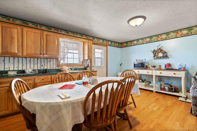 dining room featuring a textured ceiling and light wood-type flooring