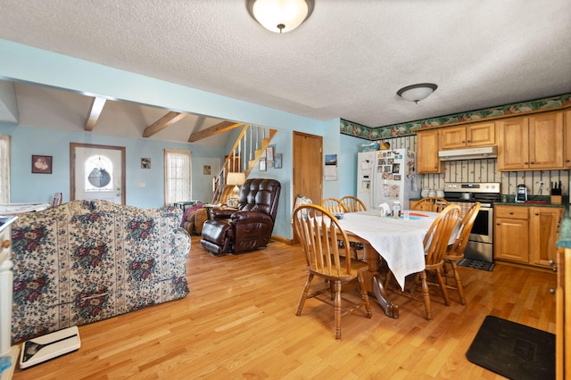 dining space with a textured ceiling, vaulted ceiling with beams, and light hardwood / wood-style floors