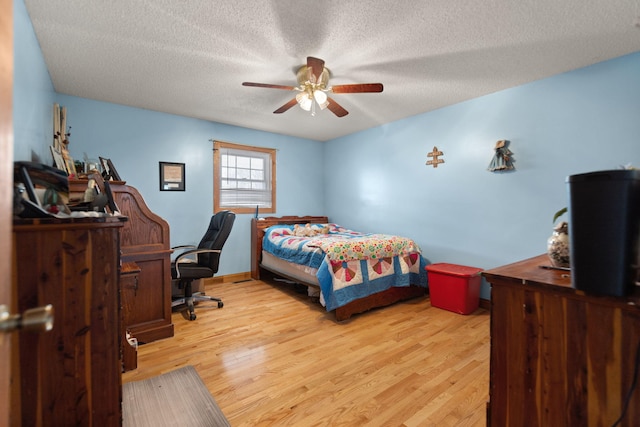 bedroom featuring a textured ceiling, light wood-type flooring, and ceiling fan