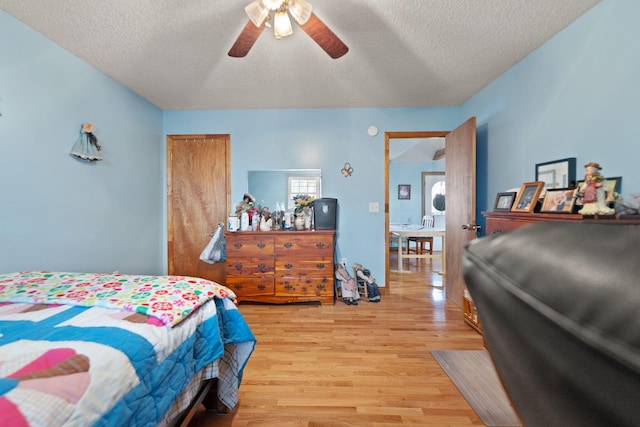 bedroom featuring ceiling fan, light hardwood / wood-style flooring, and a textured ceiling