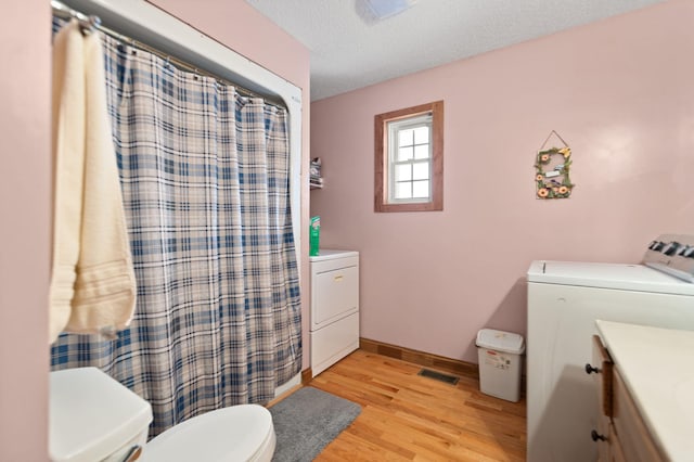 bathroom featuring vanity, toilet, washing machine and dryer, a textured ceiling, and wood-type flooring