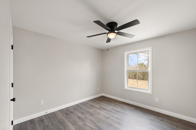 unfurnished room with dark wood finished floors, a ceiling fan, and baseboards