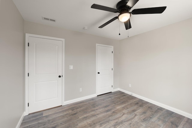 unfurnished bedroom with a ceiling fan, wood finished floors, visible vents, and baseboards