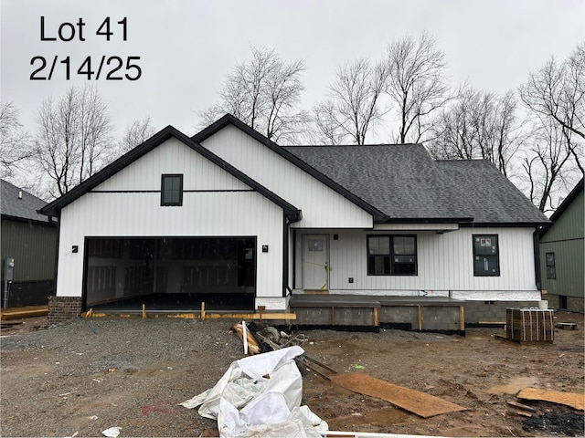 modern inspired farmhouse with a garage, gravel driveway, and a shingled roof