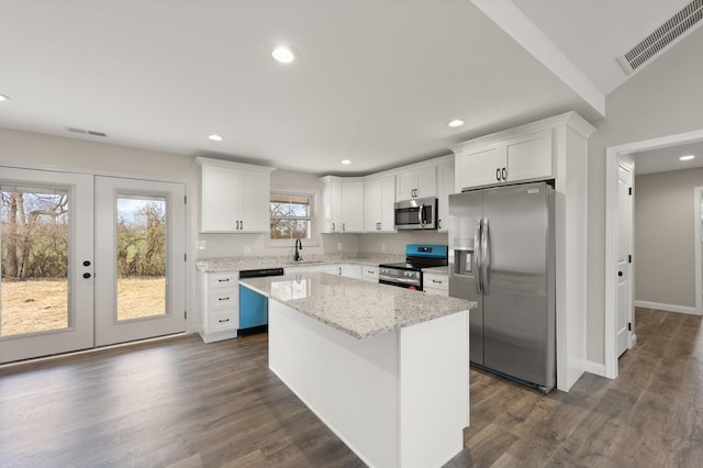 kitchen with stainless steel appliances, visible vents, a sink, and dark wood-type flooring