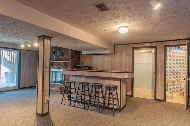 bar with light carpet, wood walls, and a textured ceiling