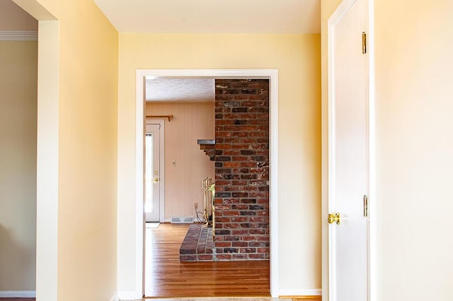 corridor with hardwood / wood-style flooring, crown molding, and wooden walls