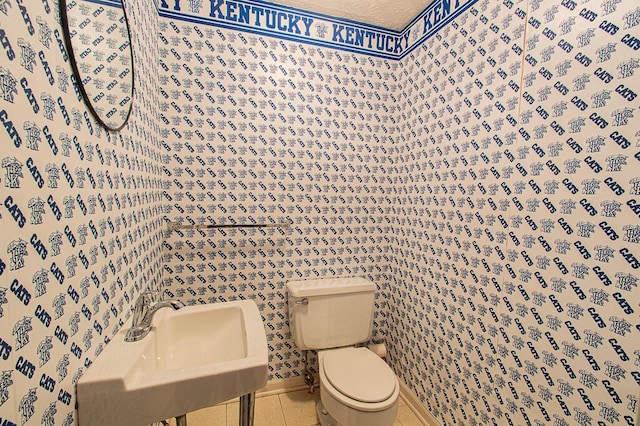 bathroom featuring a textured ceiling, toilet, sink, and tile patterned floors