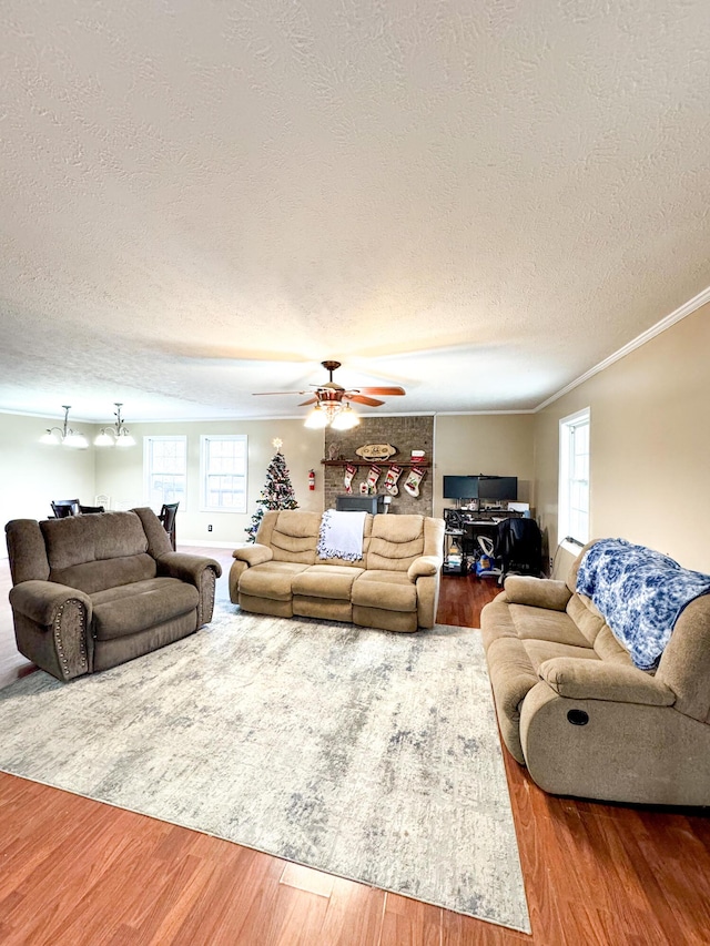 living room featuring hardwood / wood-style flooring, ceiling fan, crown molding, and a textured ceiling