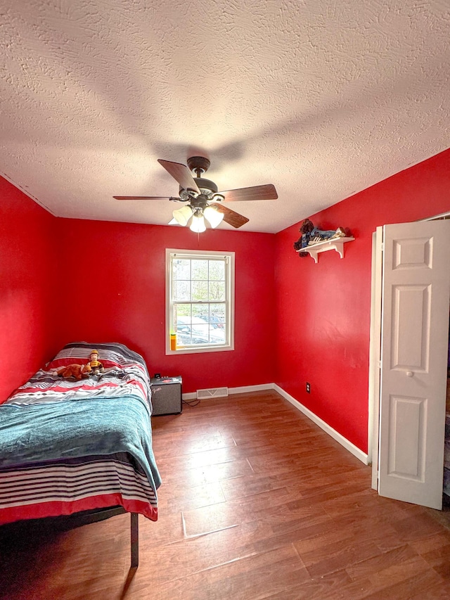 bedroom featuring ceiling fan, wood-type flooring, and a textured ceiling