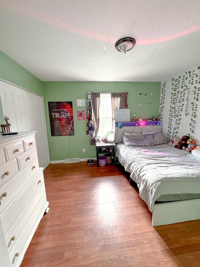 bedroom featuring a closet, wood-type flooring, and a textured ceiling