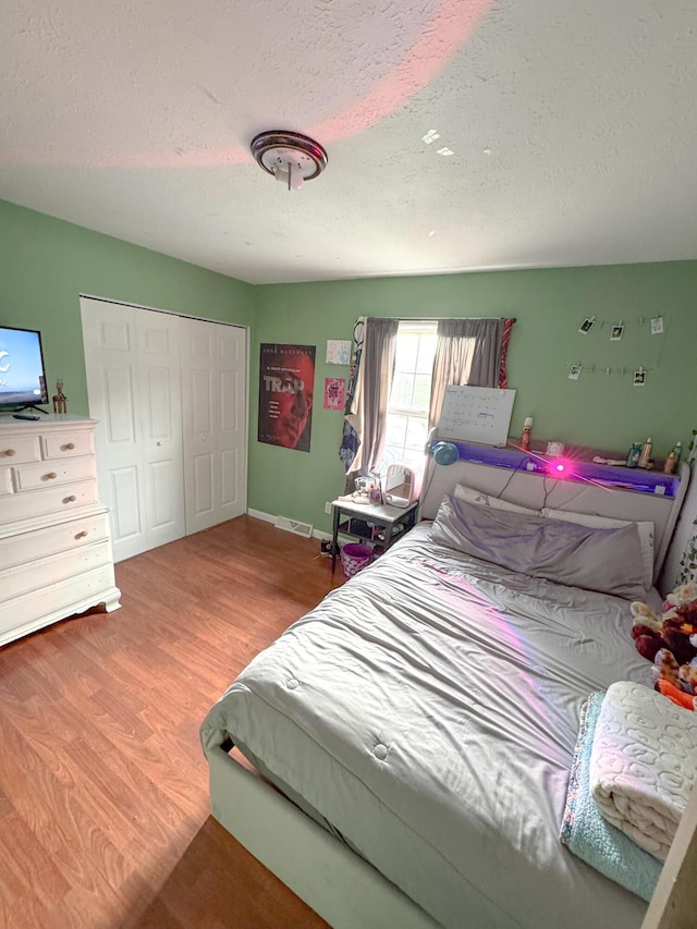 bedroom featuring hardwood / wood-style flooring, a textured ceiling, and a closet