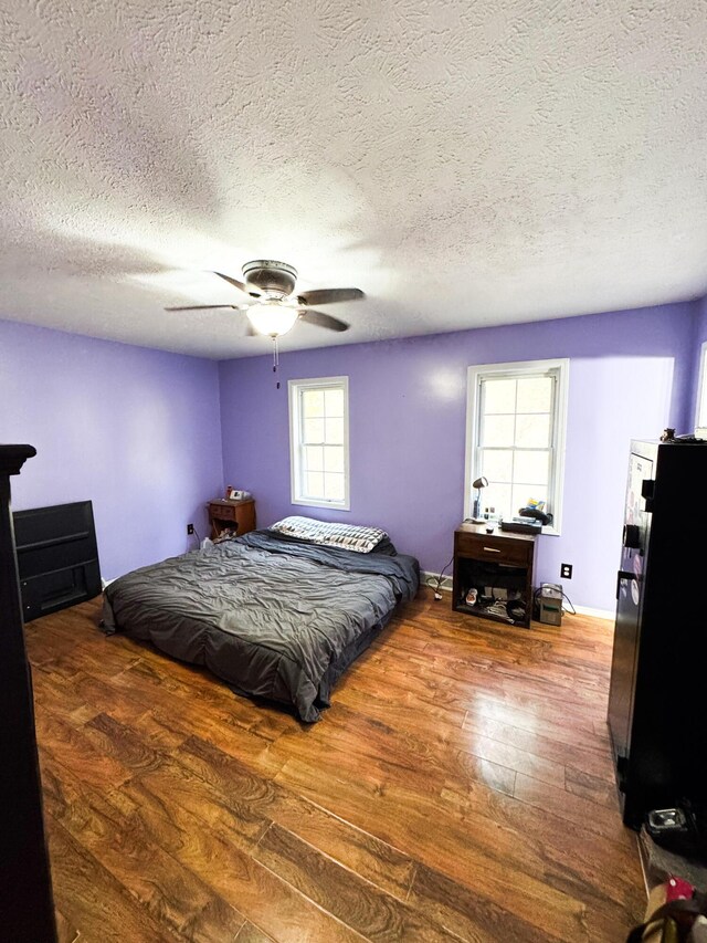 bedroom with hardwood / wood-style floors, ceiling fan, and multiple windows