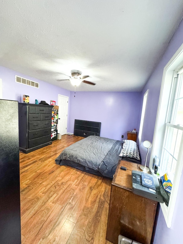 bedroom with hardwood / wood-style floors, a textured ceiling, and ceiling fan