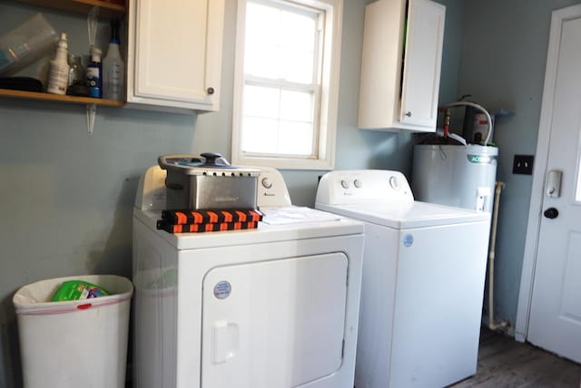 clothes washing area featuring water heater, washer and clothes dryer, cabinets, and dark hardwood / wood-style floors