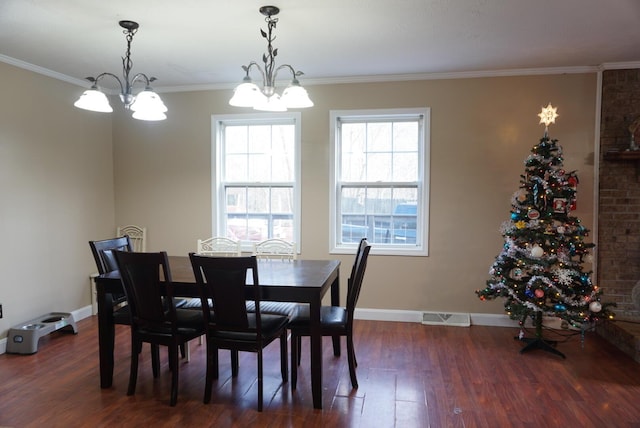 dining room featuring dark hardwood / wood-style floors, crown molding, and an inviting chandelier