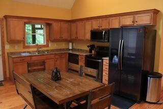 kitchen with black appliances, light hardwood / wood-style floors, lofted ceiling, and sink