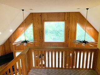 bonus room with carpet flooring, wooden walls, ceiling fan, and lofted ceiling