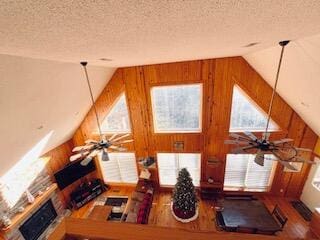 unfurnished living room with hardwood / wood-style floors, ceiling fan, lofted ceiling, and a textured ceiling