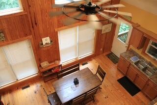 living room featuring light wood-type flooring, ceiling fan, and wooden walls