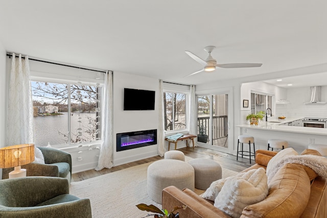 living room featuring a wealth of natural light, sink, and light wood-type flooring